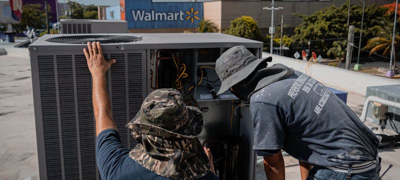 HVAC technicians inspecting an outdoor air conditioning unit on a rooftop